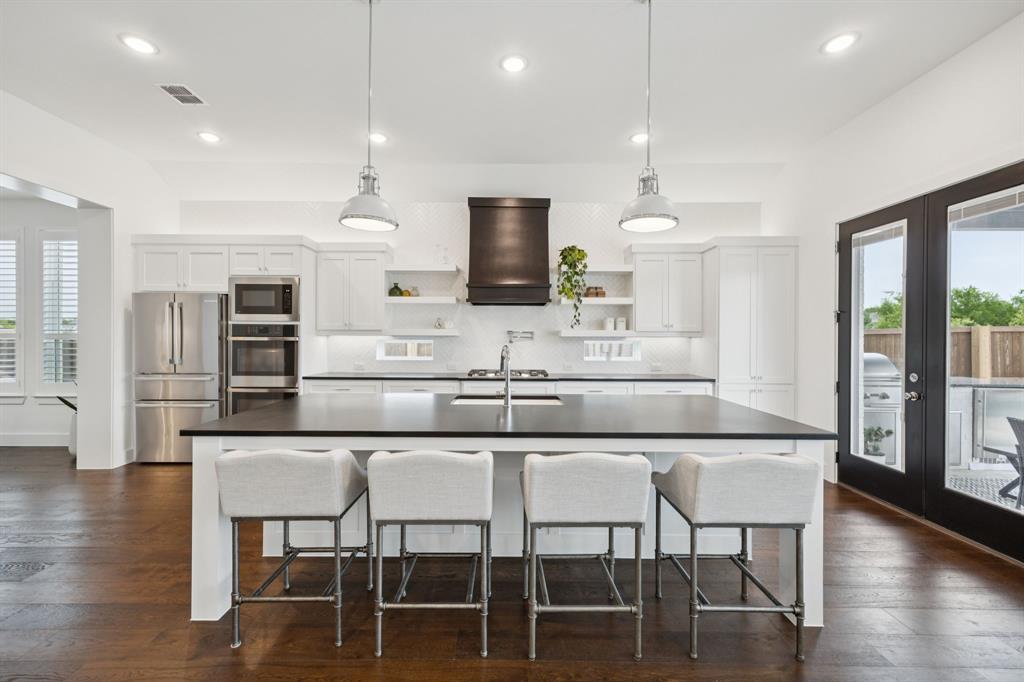 7024 Prairie Ridge Road Argyle, TX 76226 - Photo 8 of 40 Spacious Island Anchored by Dramatic Black Range Hood and Elegant Pendant Lights
