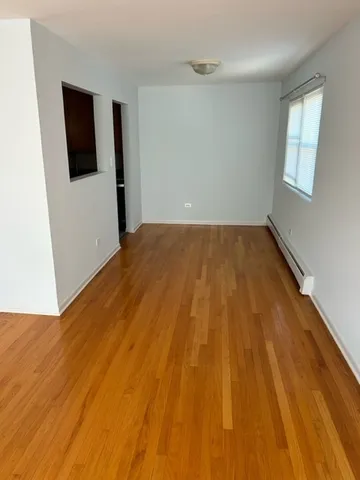 a view of an empty room with wooden floor and a window