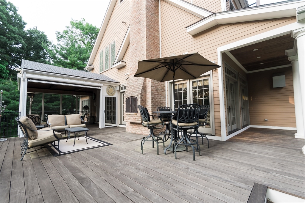 56 Sears Road Southborough, MA 01772 - Photo 23 of 26 a view of a patio with table and chairs under an umbrella with wooden floor
