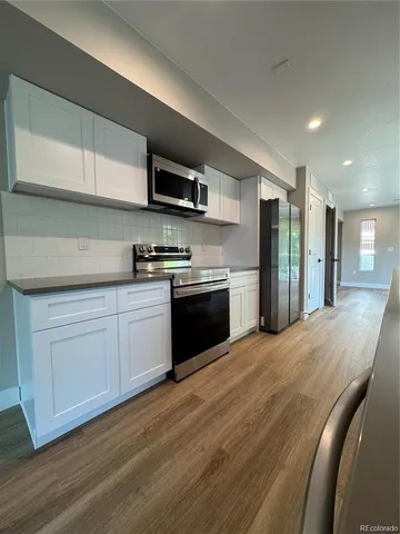 a kitchen with stainless steel appliances granite countertop a refrigerator a sink dishwasher a microwave oven with cabinets and wooden floor