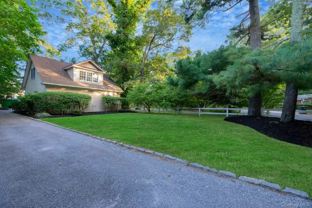 a view of a white house with a big yard and potted plants