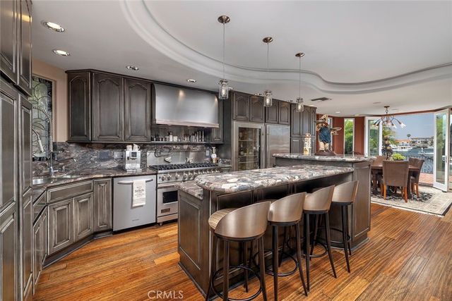 a kitchen with stainless steel appliances granite countertop table chairs sink and cabinets