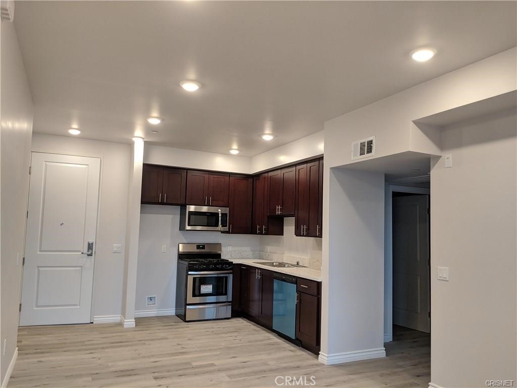 7343 Reseda Boulevard, Unit 303 Reseda, CA 91335 - Photo 3 of 10 a kitchen with stainless steel appliances kitchen island granite countertop a refrigerator and a stove top oven