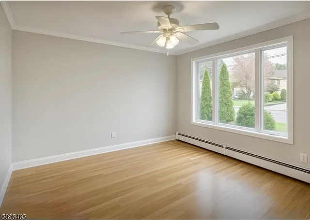 an empty room with wooden floor fan and windows
