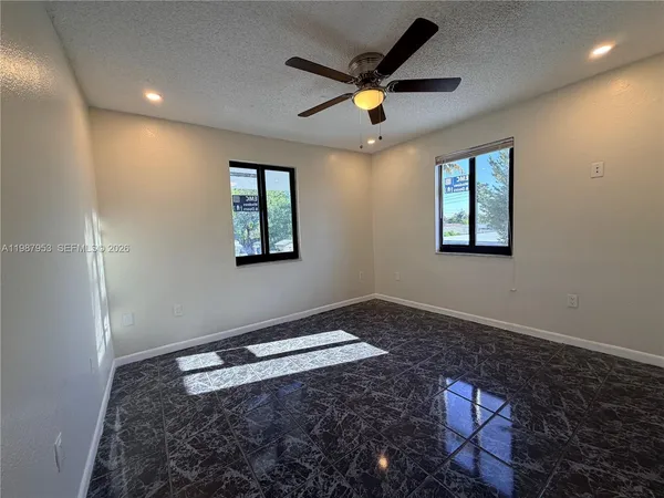 an empty room with windows and ceiling fan