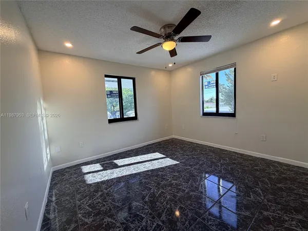an empty room with windows and ceiling fan