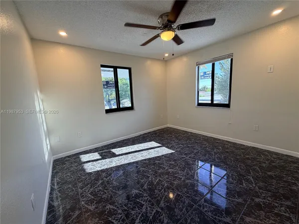 a view of empty room with window and ceiling fan