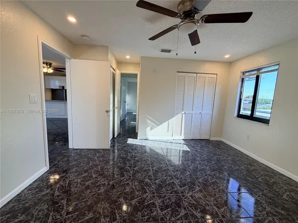 a view of empty room with window and ceiling fan