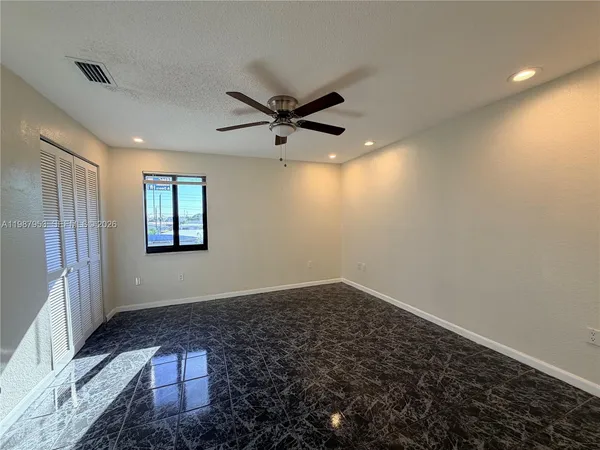 an empty room with windows and fan