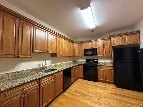 a kitchen with stainless steel appliances granite countertop a refrigerator a sink dishwasher a stove top oven and a granite countertops with wooden floor