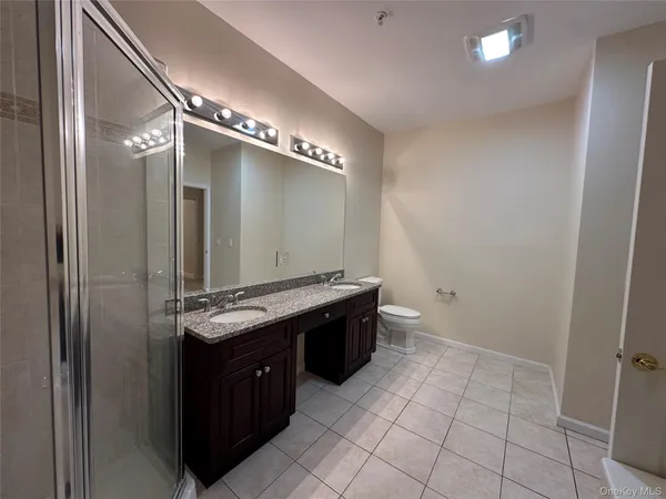 a bathroom with a granite countertop sink a toilet and shower