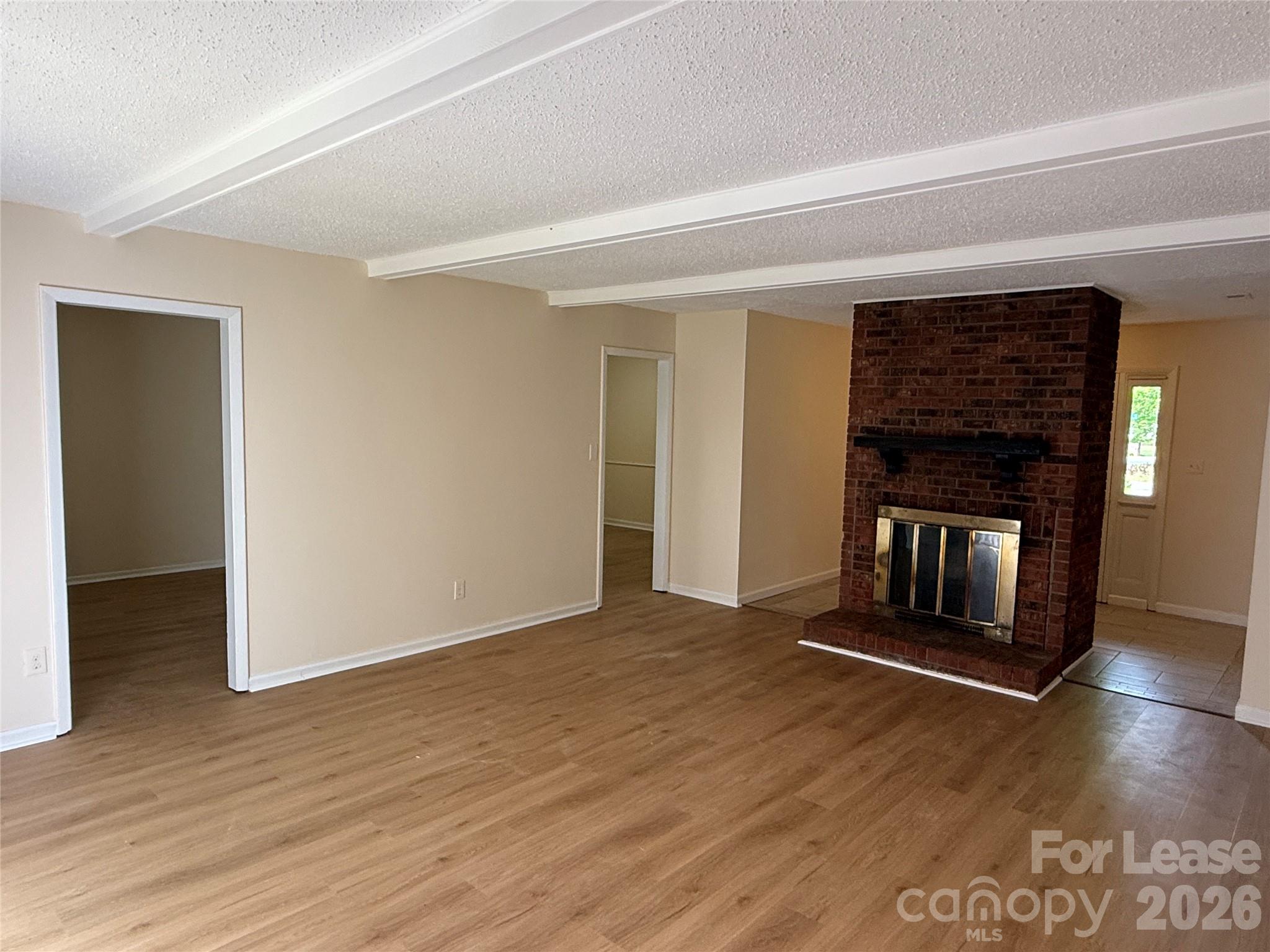 6341 Round Hill Road Charlotte, NC 28211 - Photo 3 of 16 an empty room with wooden floor fireplace and windows