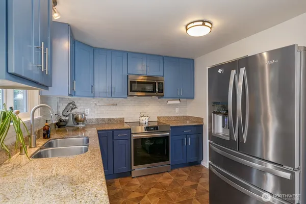 a kitchen with stainless steel appliances granite countertop a refrigerator stove and sink
