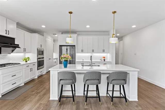 a kitchen with kitchen island granite countertop a table chairs sink and cabinets