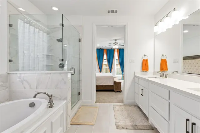 a en suite spacious bathroom with a tub double sink and mirror