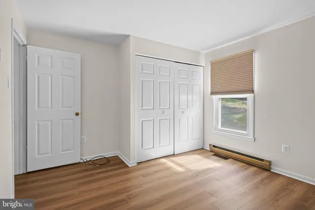 an empty room with wooden floor closet and windows