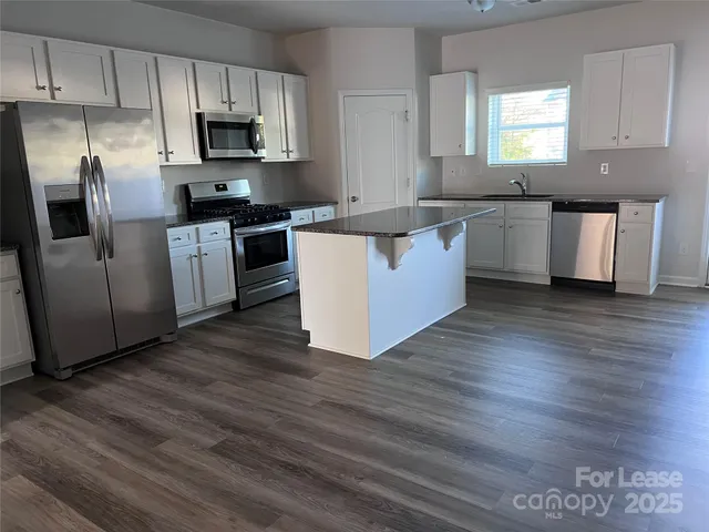 a large kitchen with stainless steel appliances wooden floors and wooden cabinets