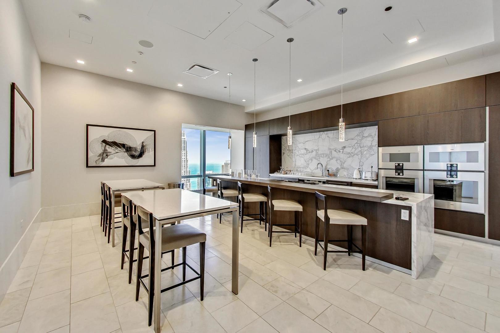363 East Wacker Drive, Unit 2708 Chicago, IL 60601 - Photo 25 of 48 a kitchen with stainless steel appliances kitchen island granite countertop a table chairs sink and cabinets