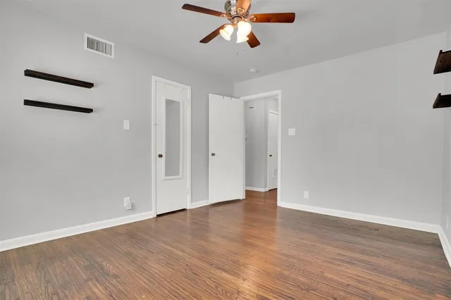 an empty room with wooden floor closet and windows
