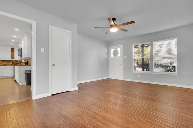 a view of an empty room with window and wooden floor
