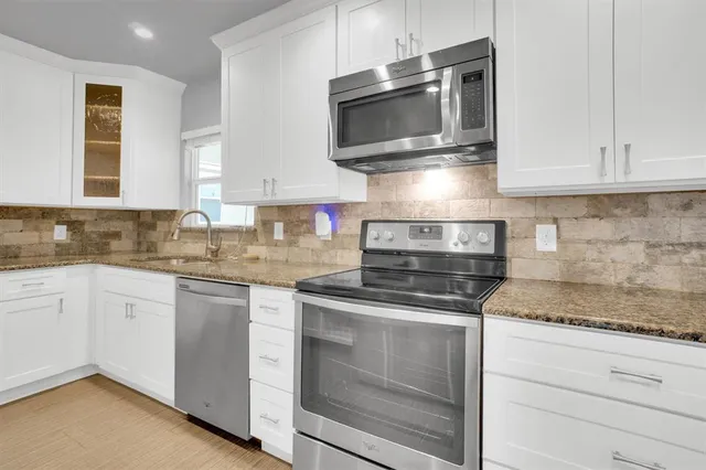 a kitchen with granite countertop white cabinets stainless steel appliances and a sink