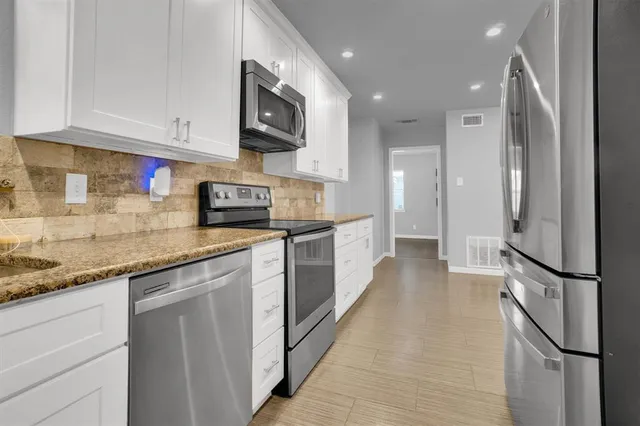 a kitchen with stainless steel appliances granite countertop a refrigerator a sink and a stove