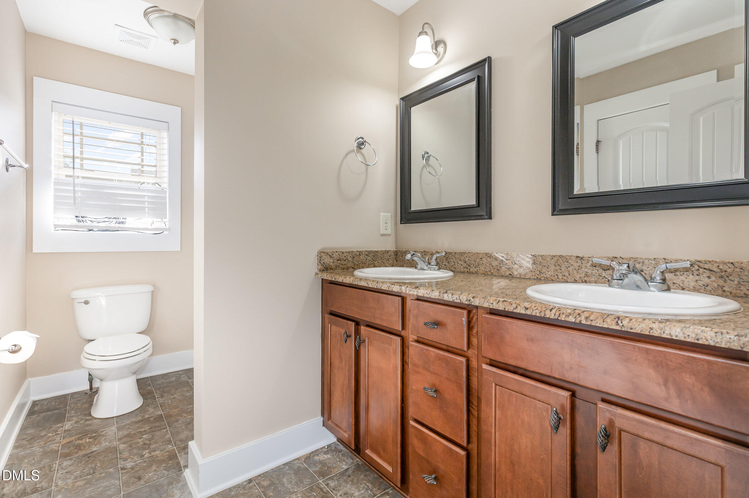 3827 Glenhaven Road Raleigh, NC 27606 - Photo 27 of 32 a bathroom with a granite countertop sink a toilet and a mirror
