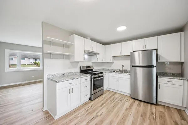 a kitchen with a white cabinets and wooden floor