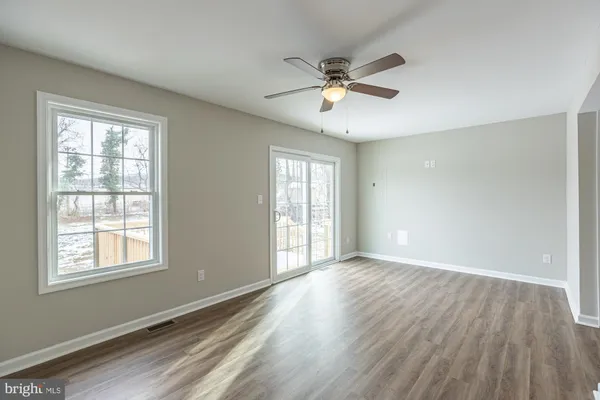 a view of an empty room with a window and wooden floor