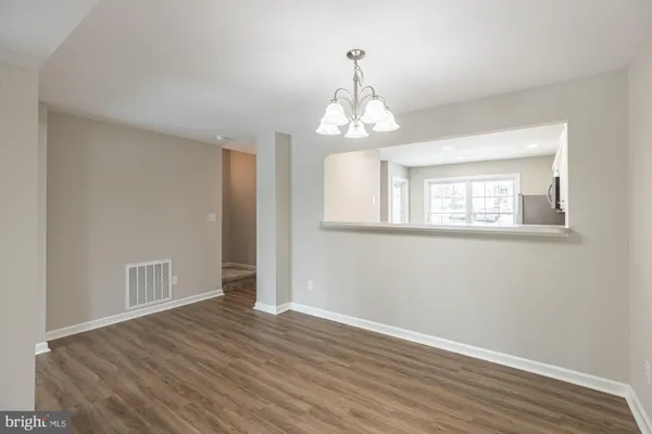 a view of empty room with wooden floor and chandelier