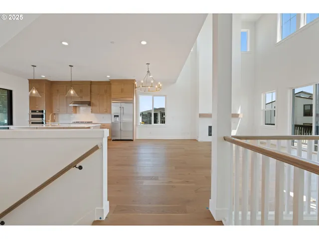 a view of a kitchen with kitchen island wooden floors and stainless steel appliances