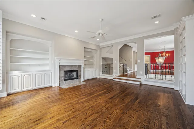 a view of an empty room with wooden floor fireplace and a window