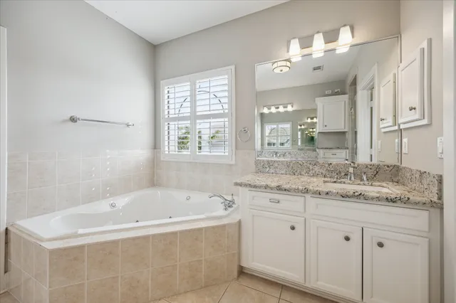 a bathroom with a granite countertop tub sink and mirror