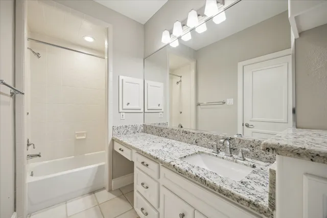 a bathroom with a granite countertop double vanity sink and mirror with bathtub