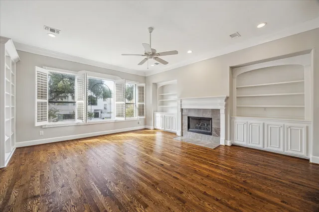 a view of an empty room with wooden floor fireplace and a window