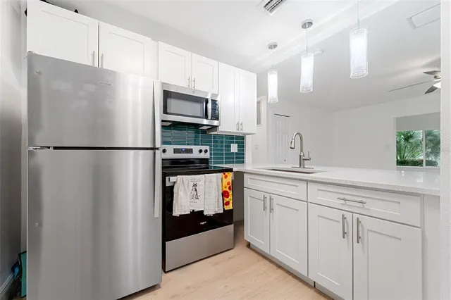 a kitchen with stainless steel appliances a refrigerator a sink a stove a microwave a center island and cabinets