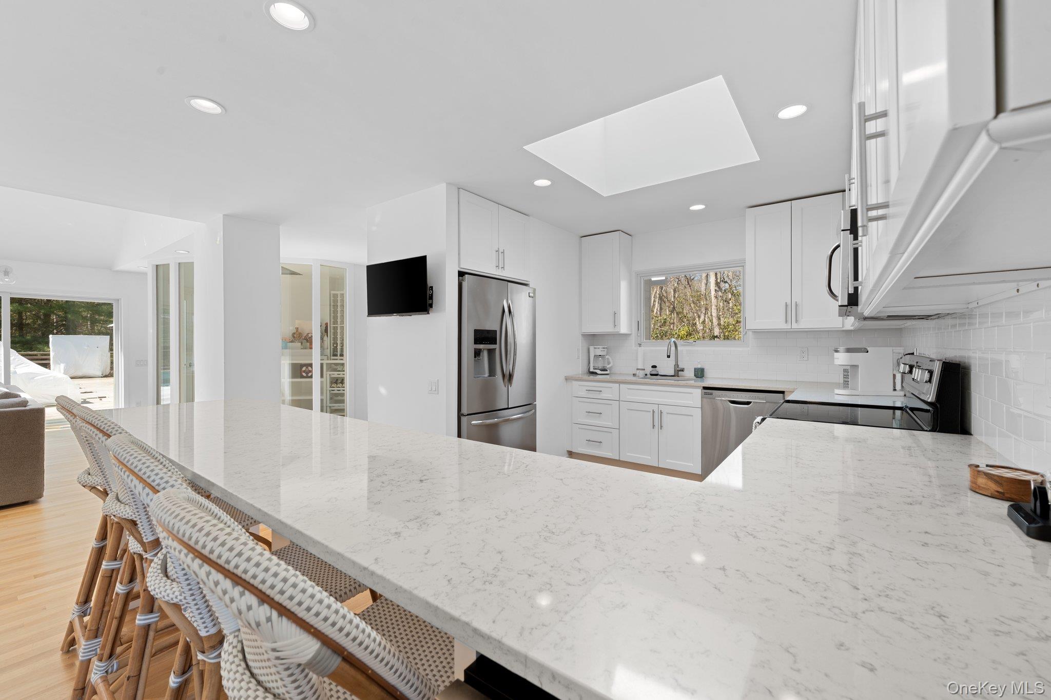 35 Ely Brook Road East Hampton, NY 11937 - Photo 20 of 32 a large white kitchen with stainless steel appliances lots of counter space and wooden floor