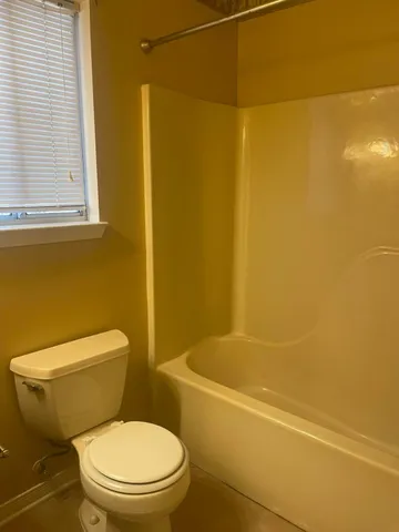 a white toilet sitting next to a bath tub