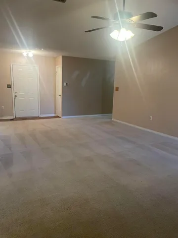 a view of an empty room with a chandelier fan