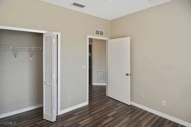 a view of an empty room with wooden floor and closet