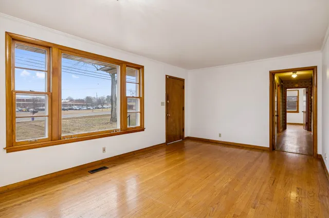 a view of an empty room with wooden floor and a window