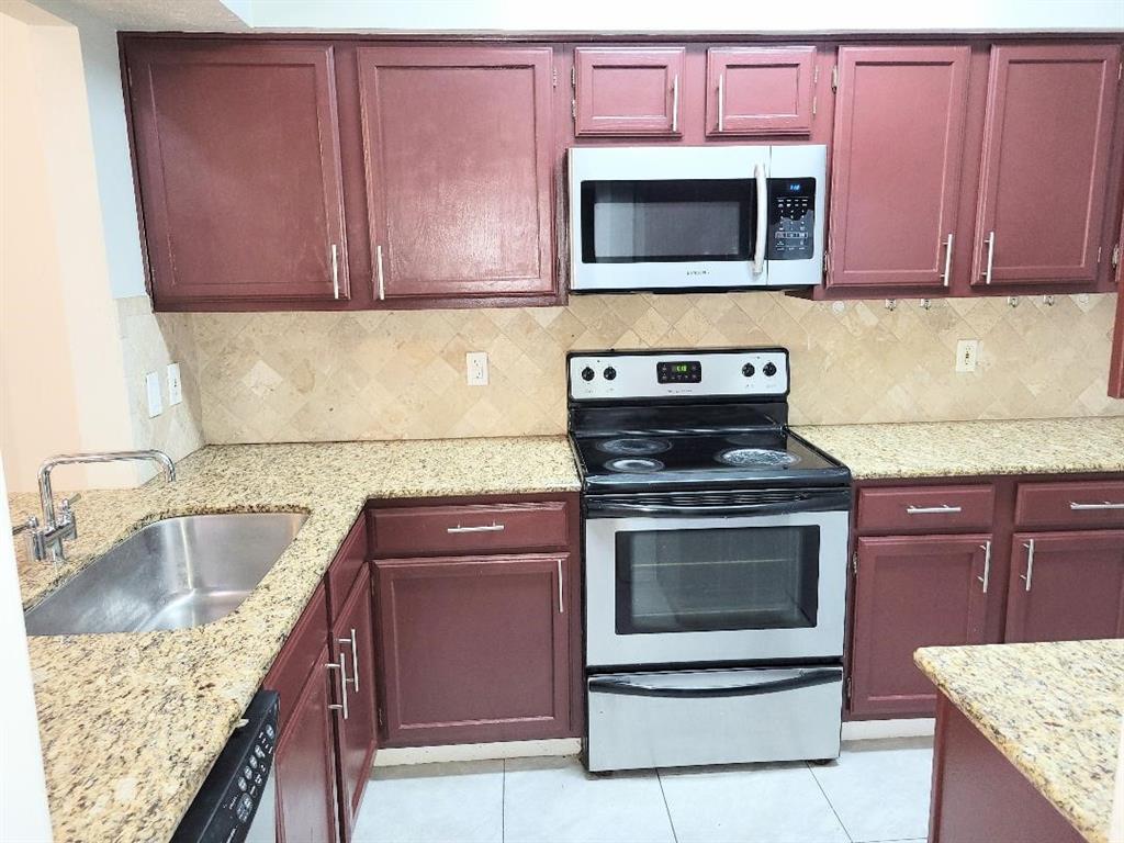 2835 Keller Springs Road, Unit 1103 Carrollton, TX 75006 - Photo 12 of 14 a kitchen with granite countertop stainless steel appliances a stove microwave and sink