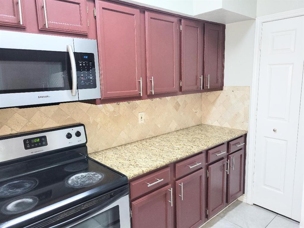 2835 Keller Springs Road, Unit 1103 Carrollton, TX 75006 - Photo 13 of 14 a kitchen with granite countertop a stove and a microwave