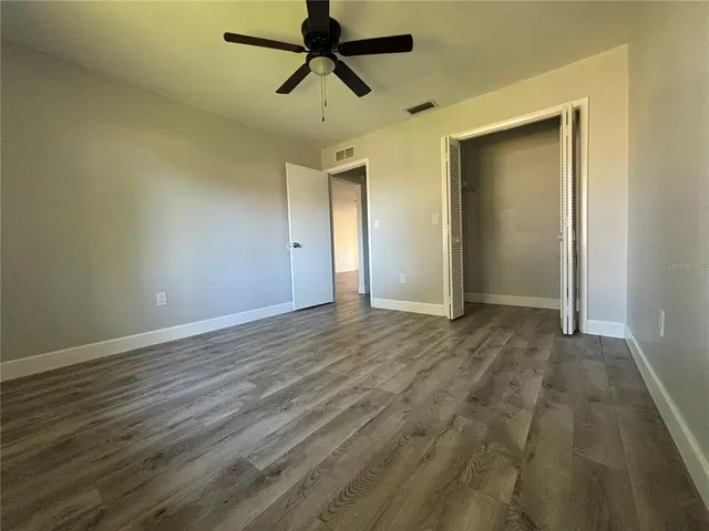 an empty room with wooden floor and windows