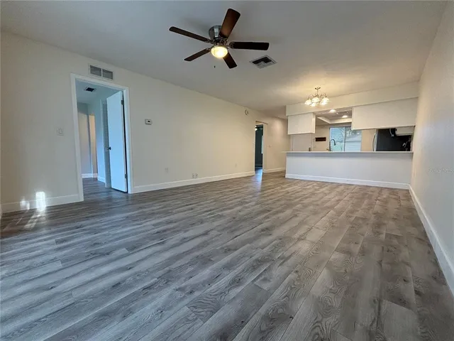 a view of kitchen and empty room with wooden floor