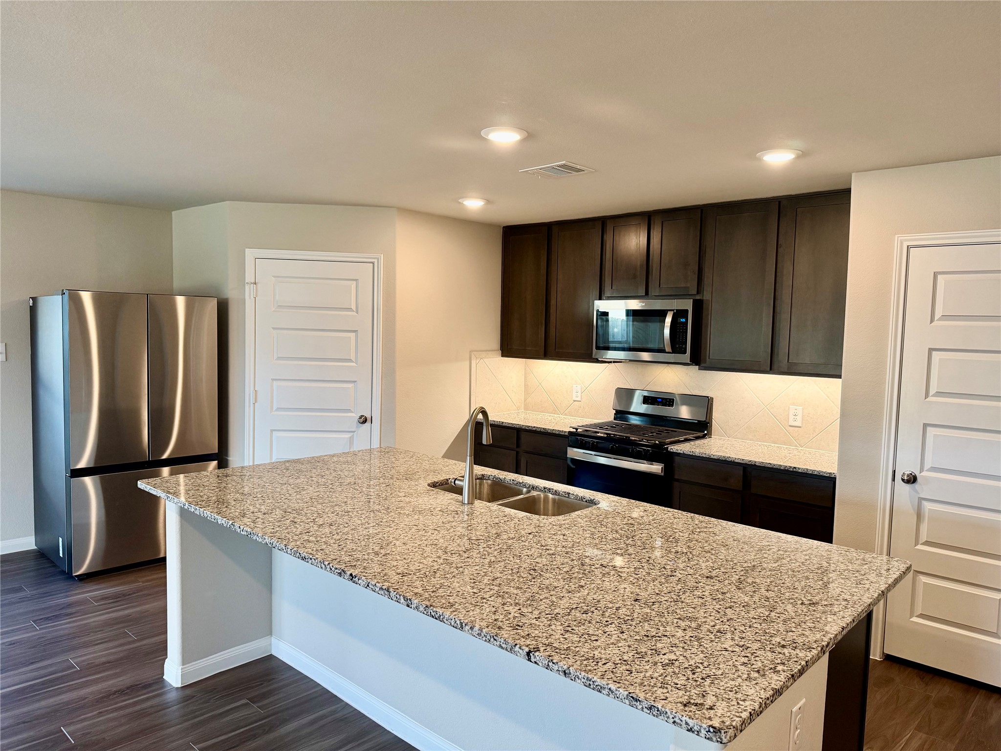5322 Briana Dee Drive Rosharon, TX 77583 - Photo 6 of 20 a kitchen with stainless steel appliances granite countertop a sink refrigerator and microwave