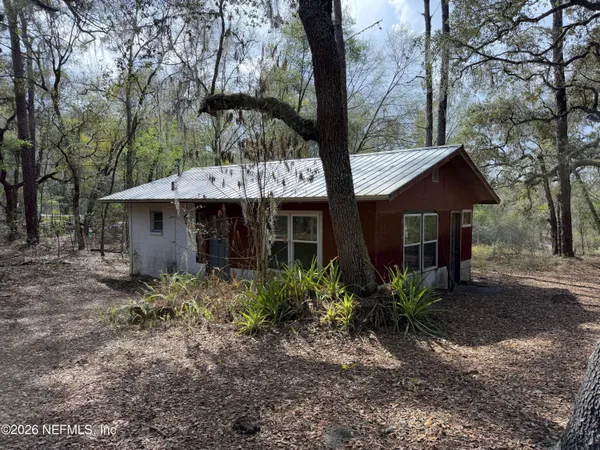 a view of a house with a yard and large trees