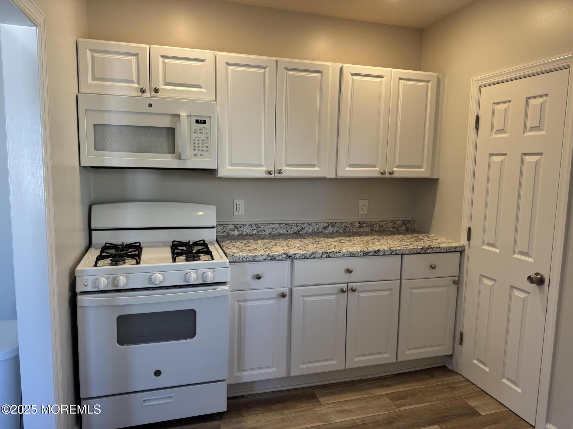 a kitchen with granite countertop white cabinets and white appliances