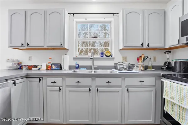 a kitchen with stainless steel appliances granite countertop a stove a sink dishwasher a refrigerator and white cabinets with wooden floor