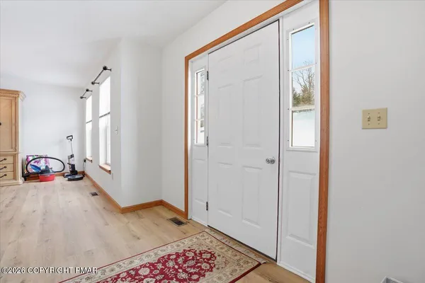 an empty room with wooden floor cabinet and windows